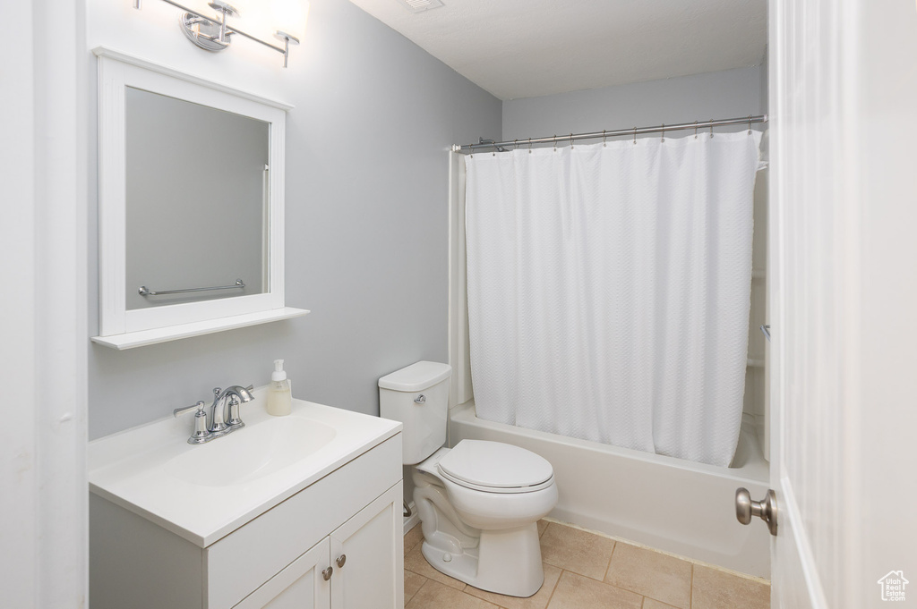 Full bath featuring shower / bath combo with shower curtain, toilet, tile patterned flooring, and vanity