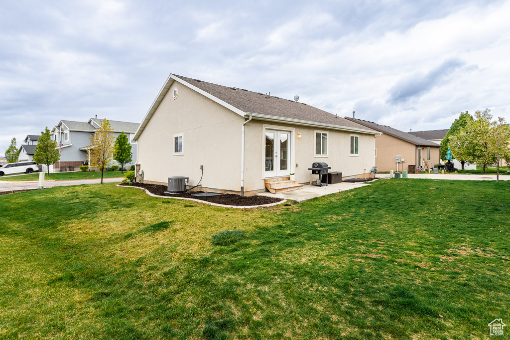 Rear view of property with a yard, cooling unit, and stucco siding