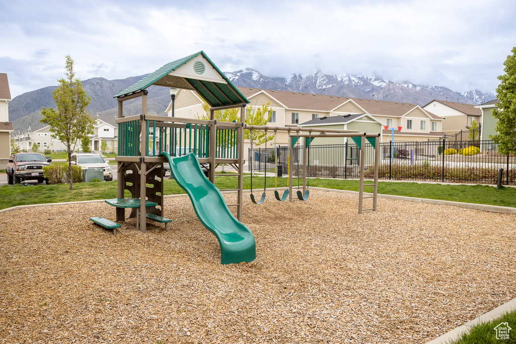 Community playground with fence, a mountain view, and a residential view