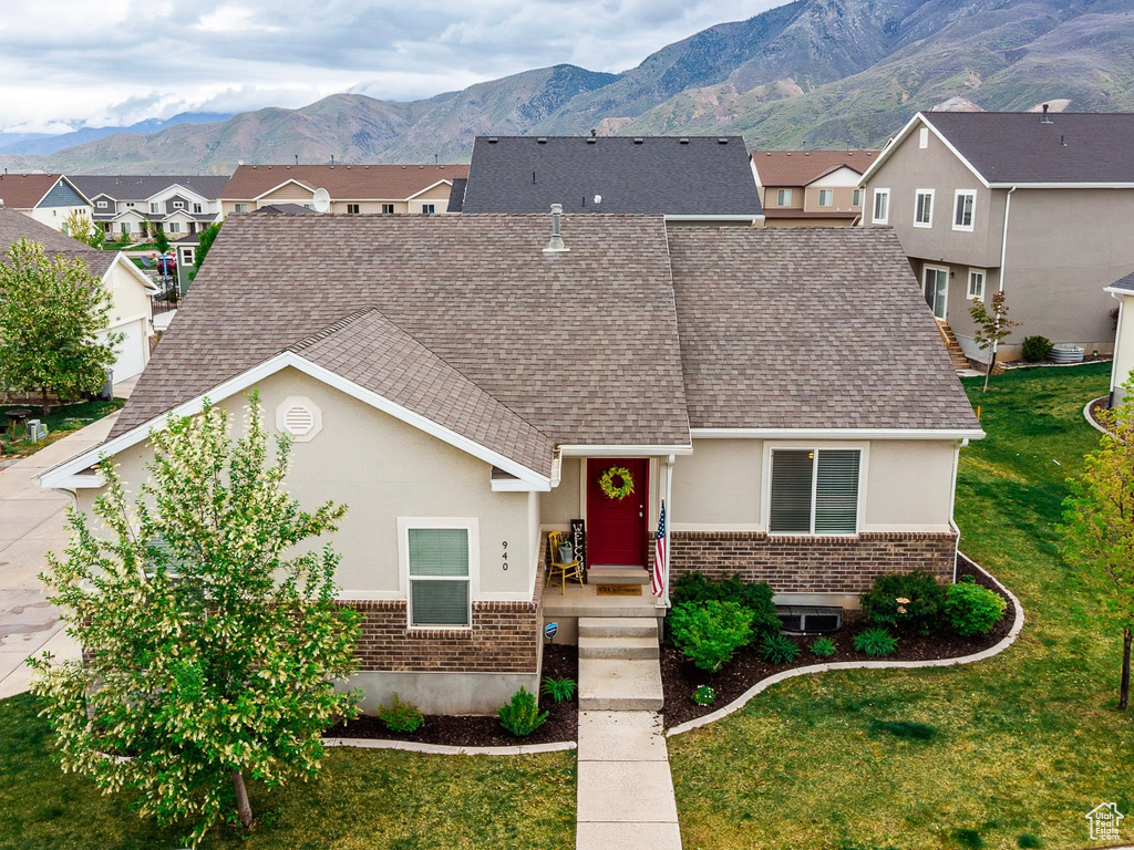 View of front of house with brick siding, roof with shingles, a mountain view, and stucco siding