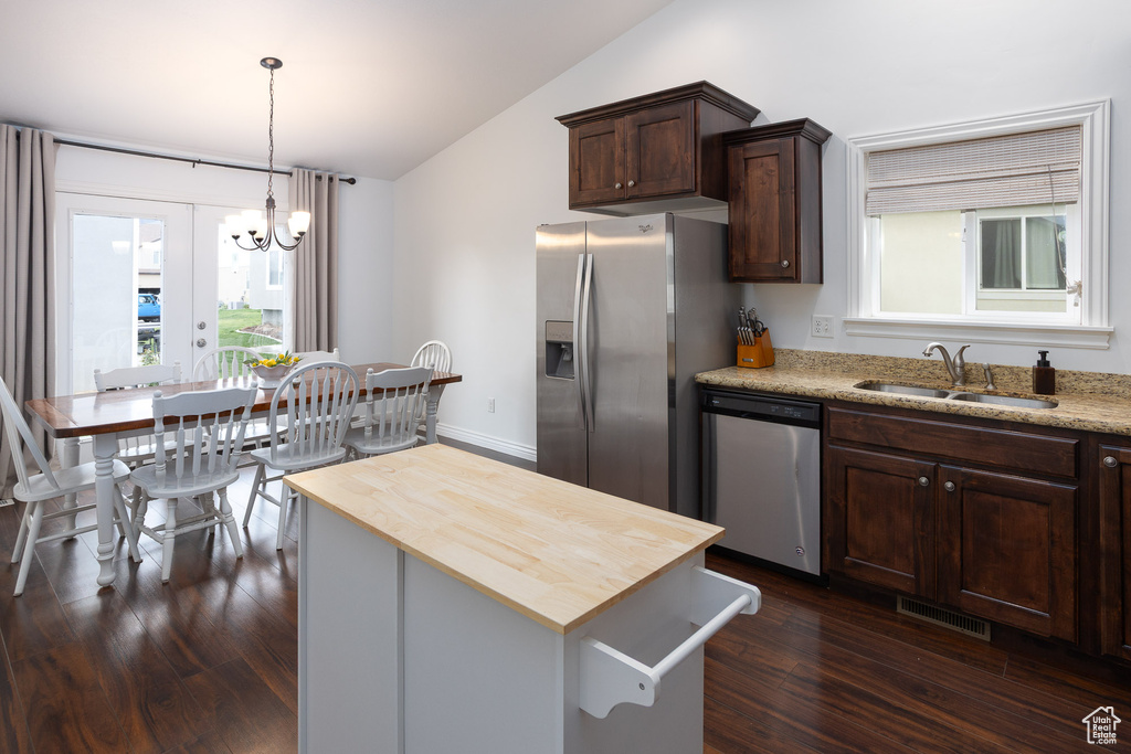 Kitchen with lofted ceiling, a chandelier, a sink, wood counters, and appliances with stainless steel finishes