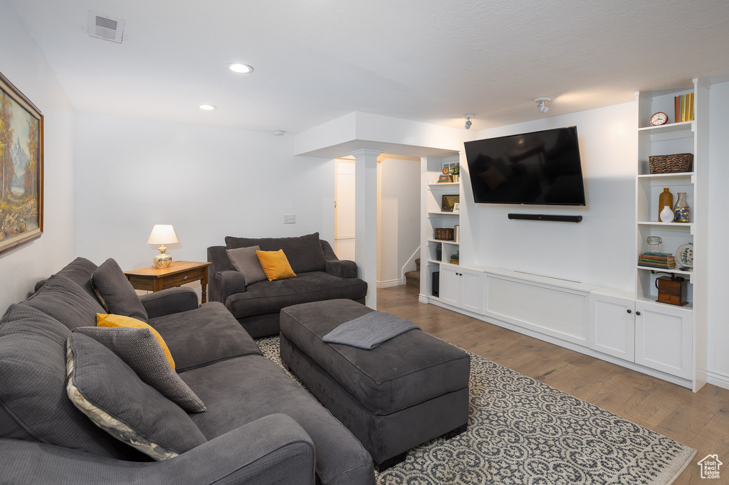 Living area featuring stairs, recessed lighting, wood finished floors, ornate columns, and visible vents