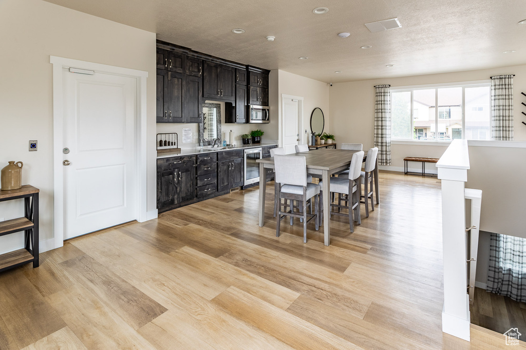 Dining room with visible vents, beverage cooler, baseboards, recessed lighting, and light wood-style flooring