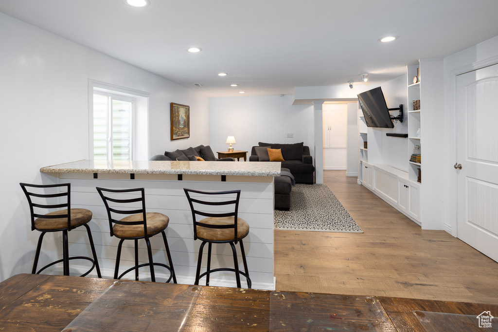 Kitchen featuring a kitchen bar, open shelves, wood finished floors, recessed lighting, and white cabinetry