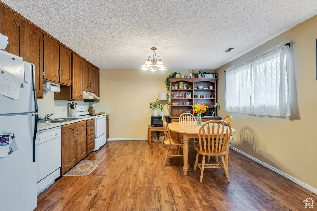 Dining room with a textured ceiling, a notable chandelier, baseboards, and light wood-style floors