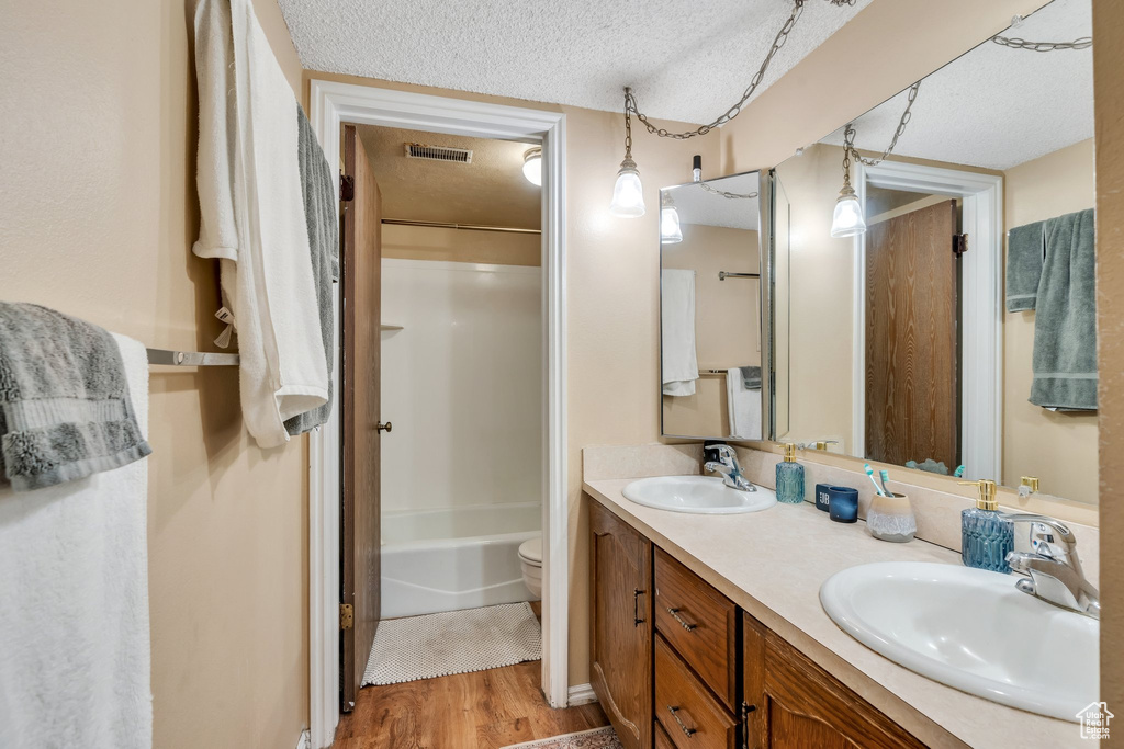 Bathroom with visible vents, a sink, a textured ceiling, and wood finished floors