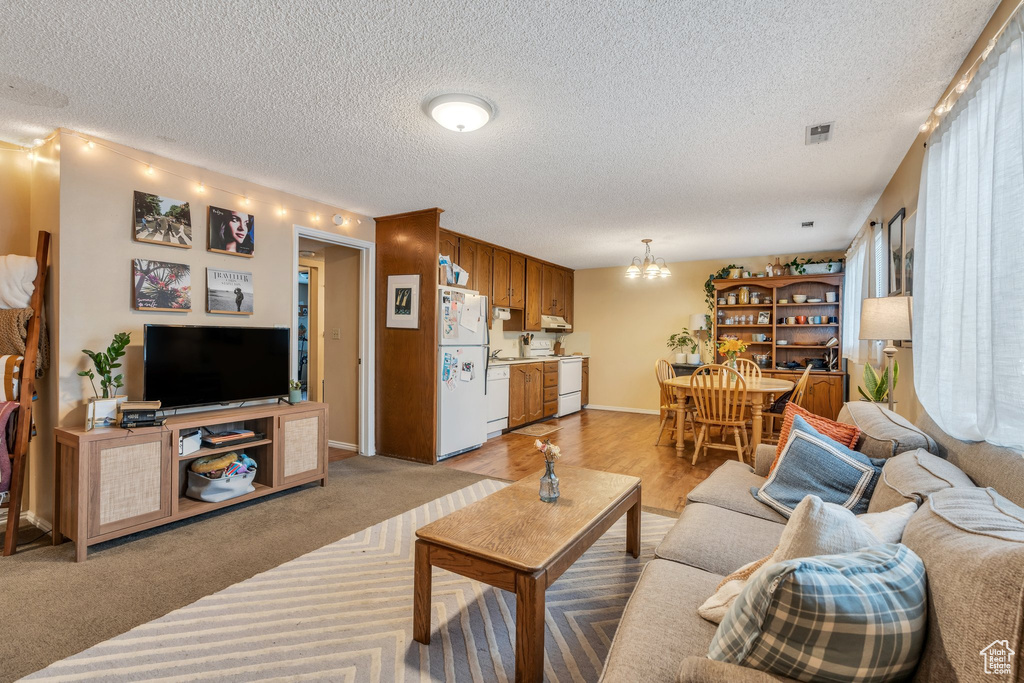 Living area featuring baseboards, a textured ceiling, visible vents, and an inviting chandelier