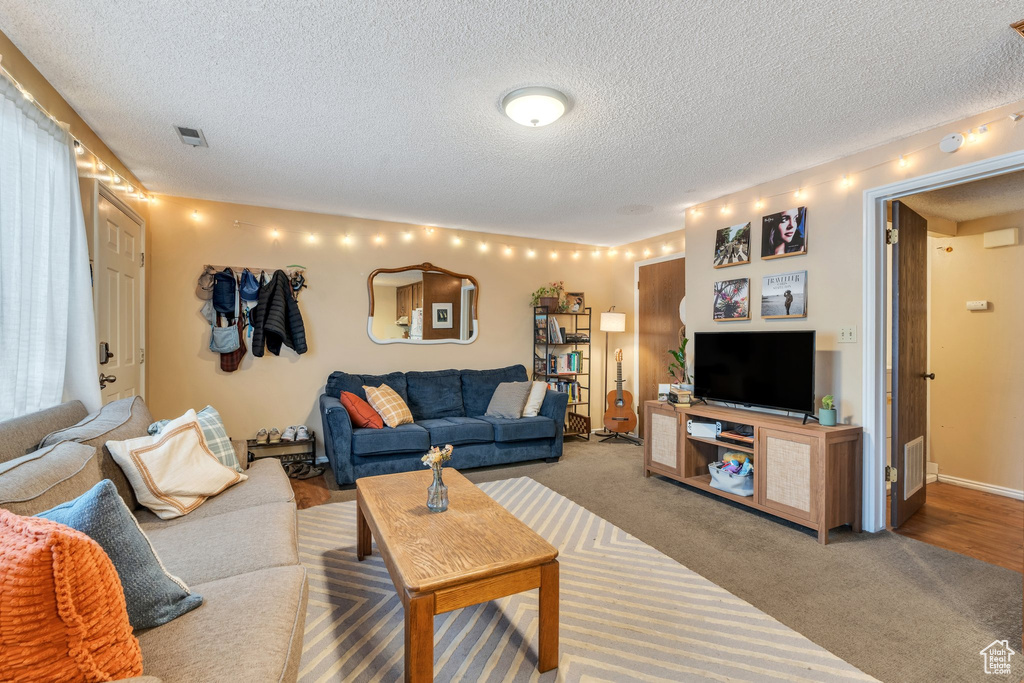 Living room featuring carpet floors, a textured ceiling, and visible vents
