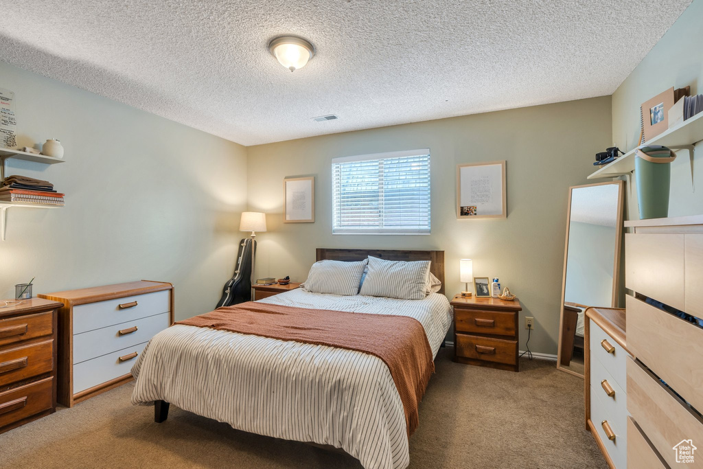 Bedroom with carpet floors, a textured ceiling, and visible vents