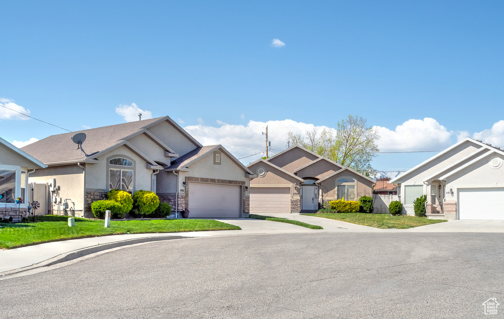 Single story home with a garage, a front yard, stone siding, stucco siding, and driveway
