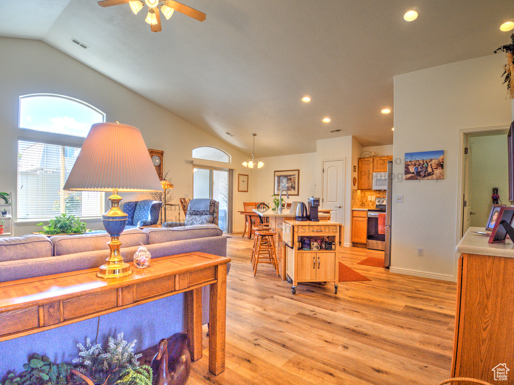 Living room featuring visible vents, recessed lighting, light wood-type flooring, ceiling fan with notable chandelier, and vaulted ceiling