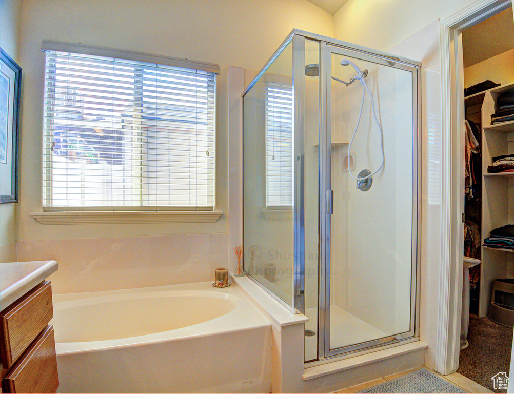 Full bathroom featuring vanity, a shower stall, a bath, and a spacious closet