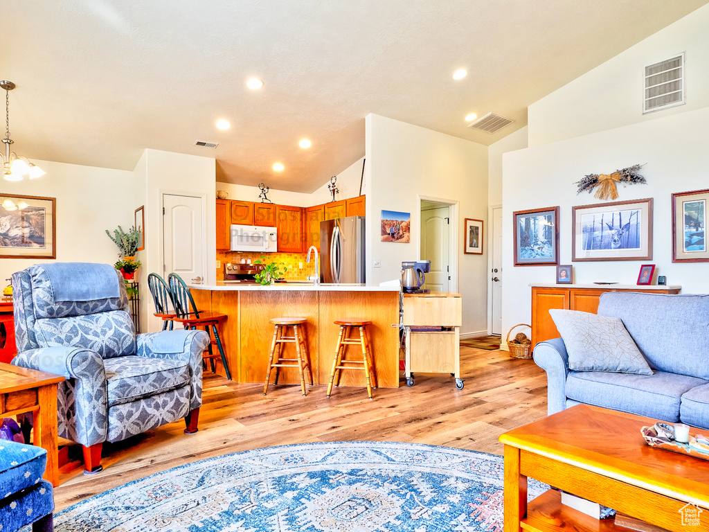 Living room with visible vents, light wood-style floors, and lofted ceiling