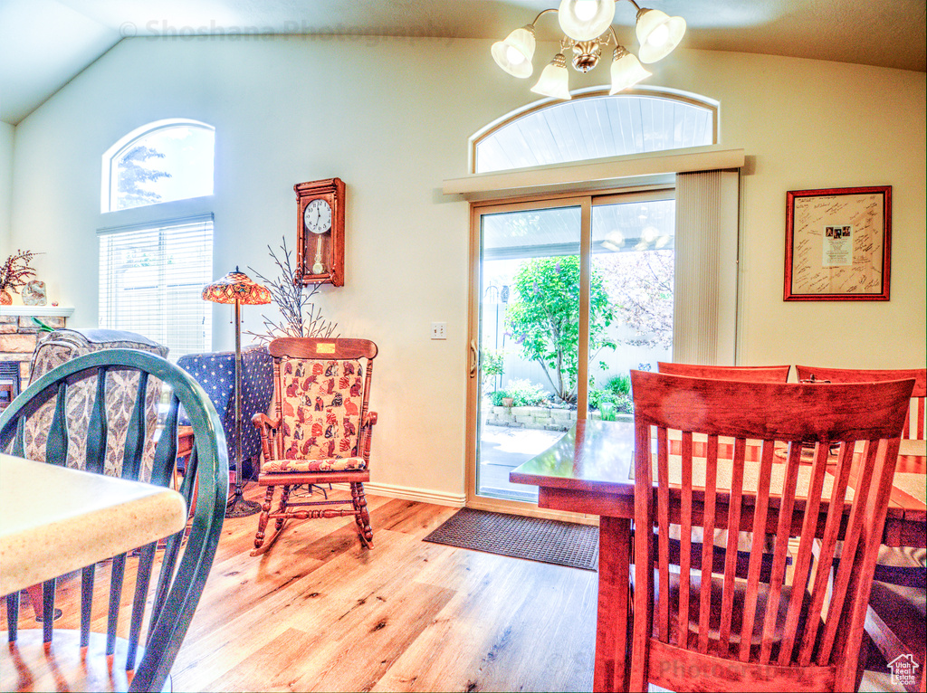 Dining area featuring a healthy amount of sunlight, vaulted ceiling, wood finished floors, and a notable chandelier
