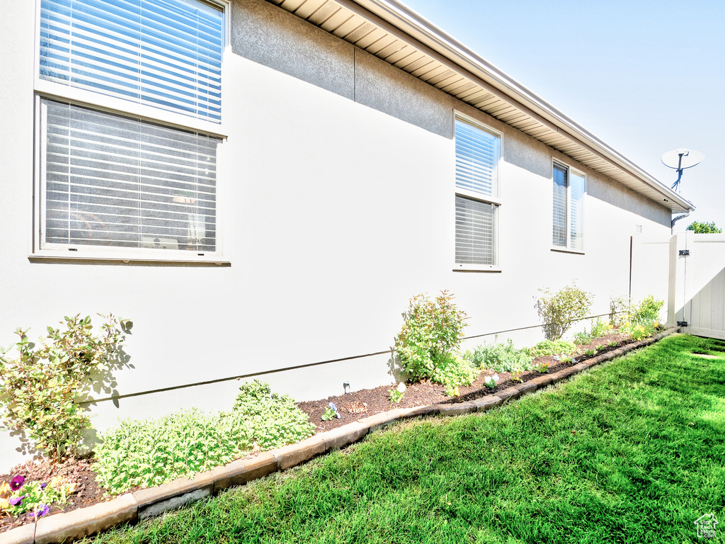 View of side of home featuring a lawn, stucco siding, and fence