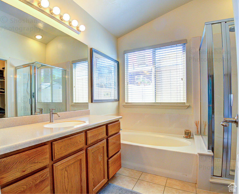 Bathroom with a garden tub, vaulted ceiling, a stall shower, vanity, and tile patterned floors