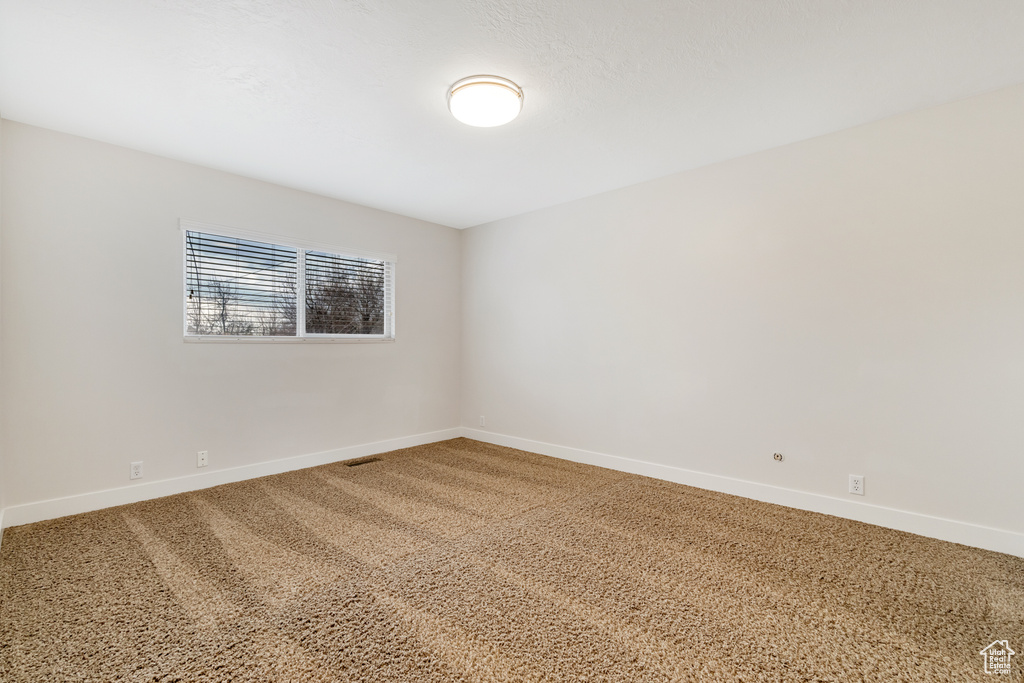 Carpeted spare room featuring baseboards and visible vents