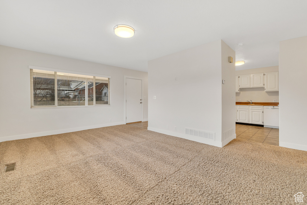 Spare room featuring baseboards, visible vents, light carpet, and a sink