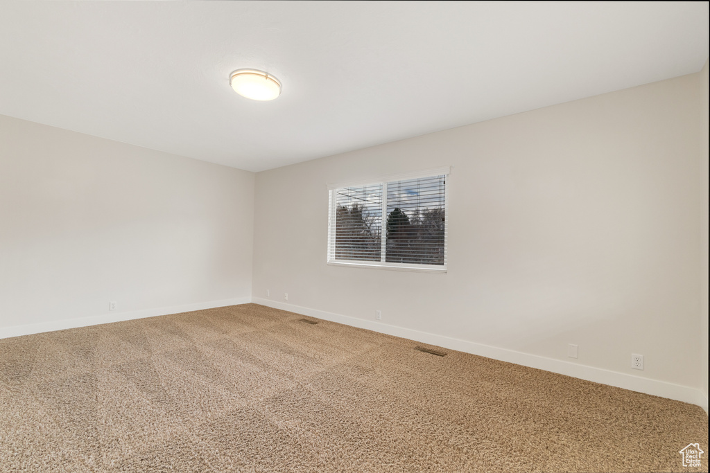 Unfurnished room featuring baseboards and light carpet