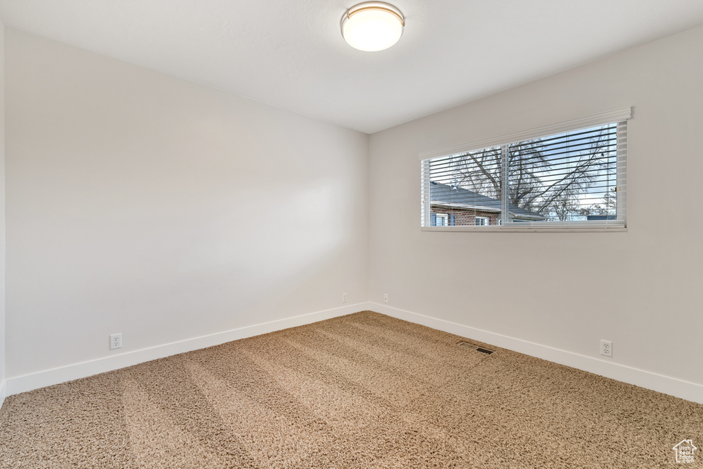 Unfurnished room featuring baseboards, carpet flooring, and visible vents