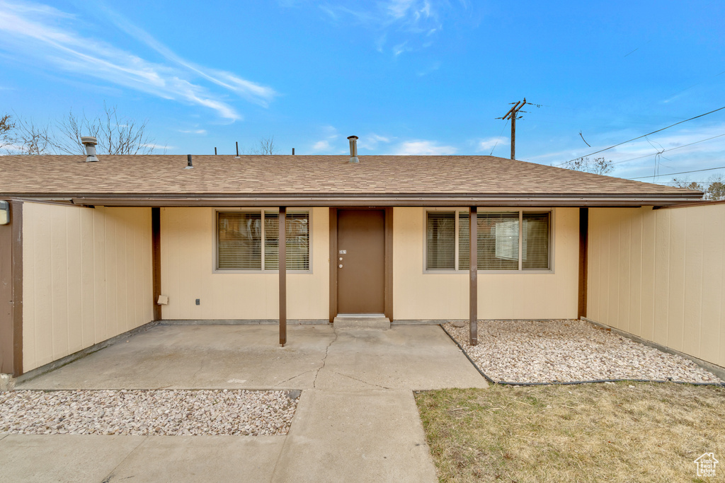 Rear view of property with a shingled roof and a patio area