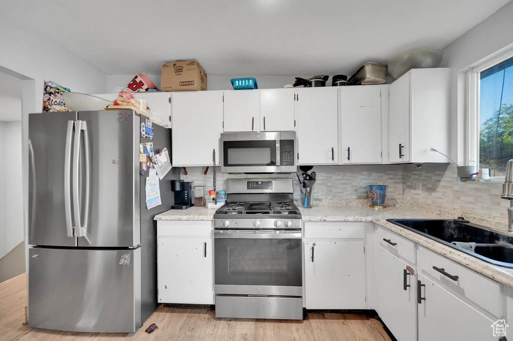 Kitchen with light countertops, white cabinets, appliances with stainless steel finishes, and a sink