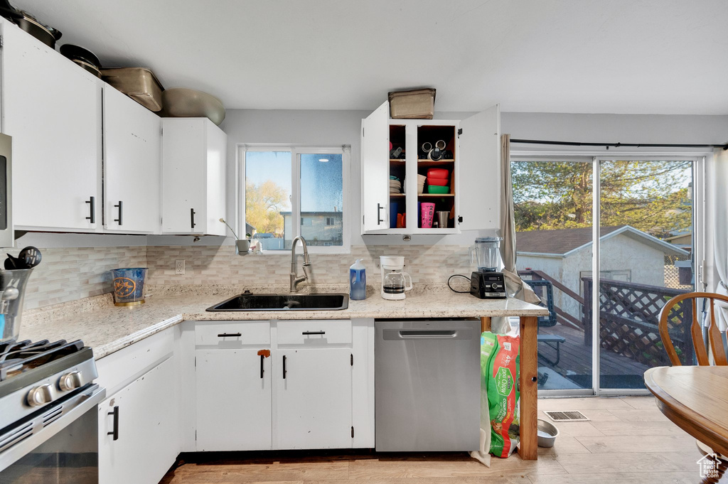 Kitchen with backsplash, stainless steel appliances, a healthy amount of sunlight, and a sink