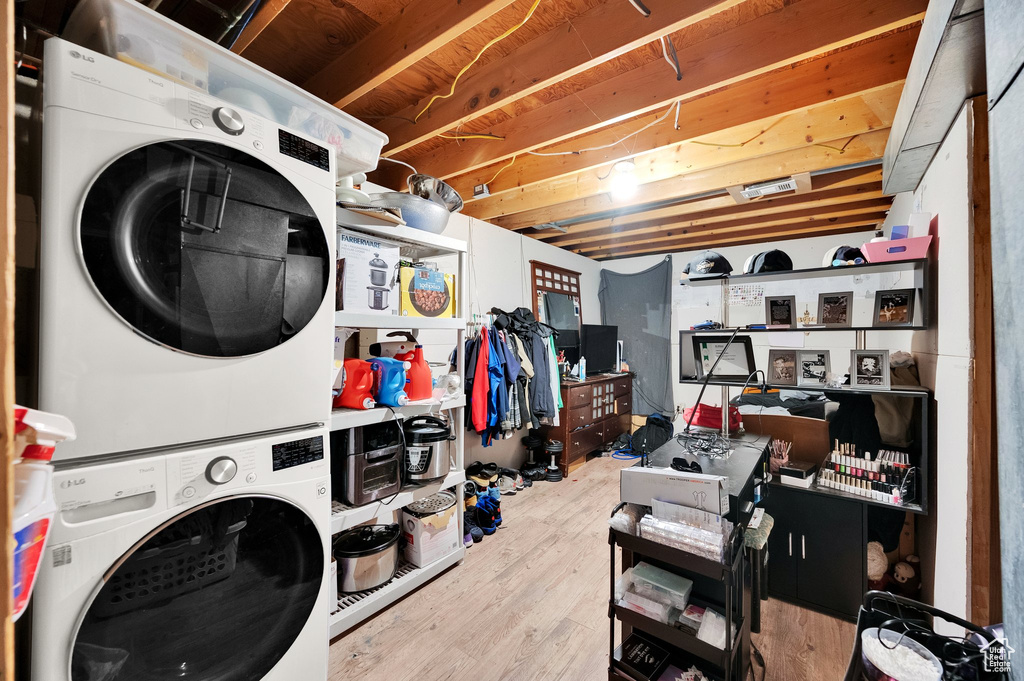 Clothes washing area featuring laundry area, stacked washing maching and dryer, and wood finished floors