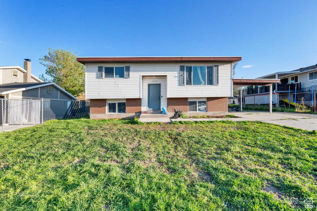 Bi-level home featuring brick siding, fence, and a carport
