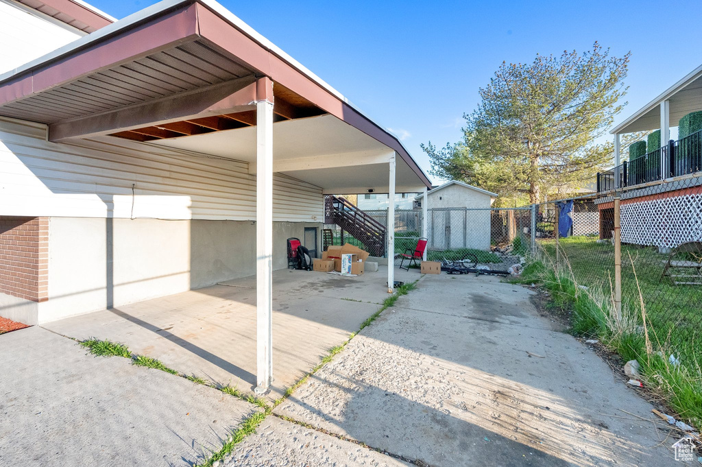 Exterior space with fence, stairs, and a carport