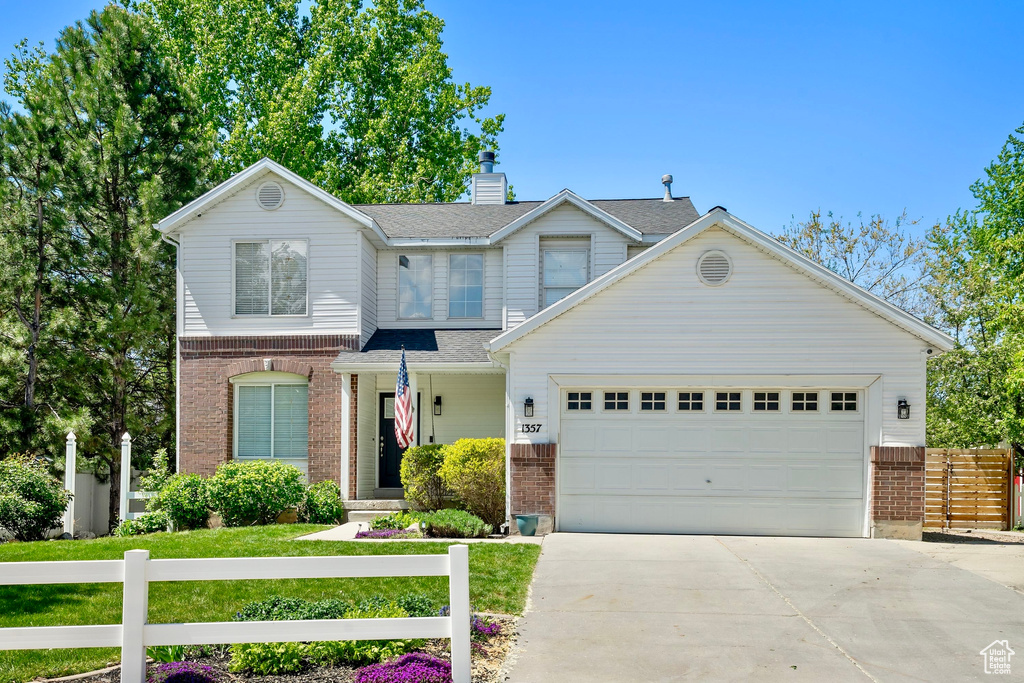 Traditional-style house featuring brick siding, fence, driveway, and a garage