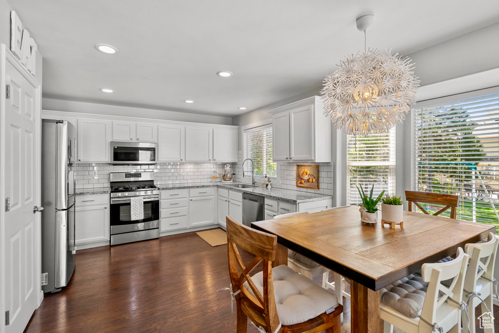 Kitchen with a sink, decorative backsplash, white cabinetry, and stainless steel appliances