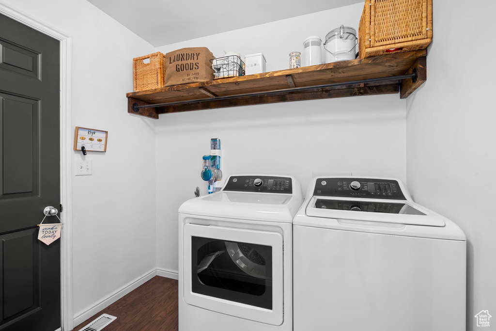 Washroom with laundry area, separate washer and dryer, dark wood finished floors, baseboards, and visible vents