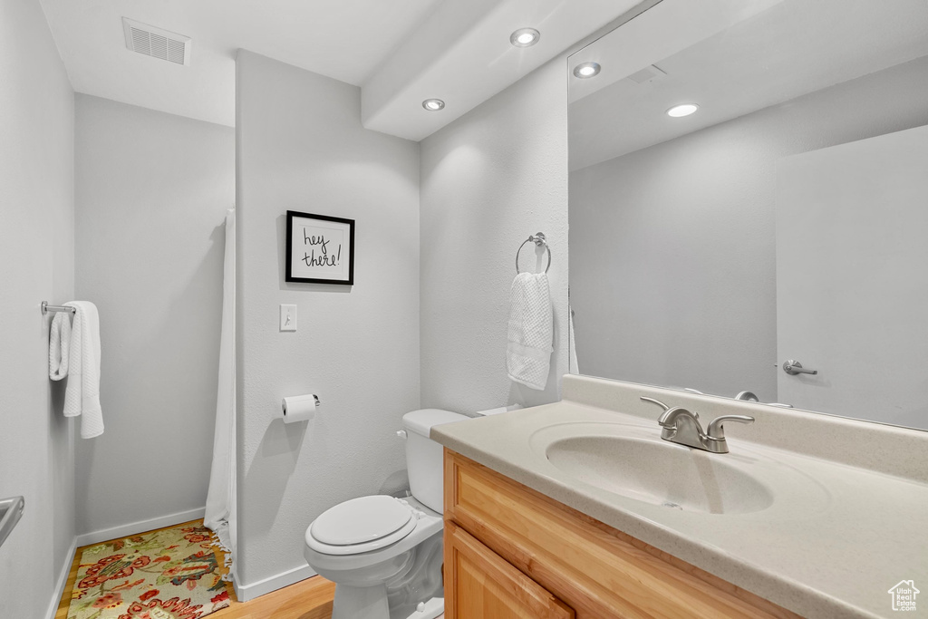 Bathroom featuring visible vents, vanity, baseboards, toilet, and recessed lighting