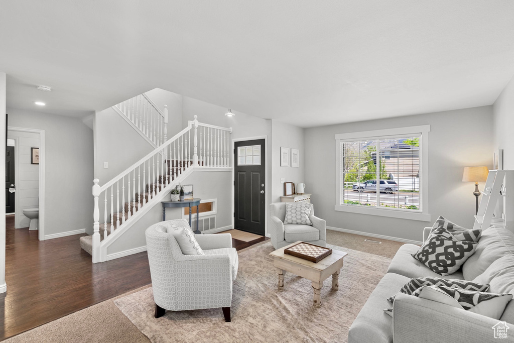 Carpeted living room featuring baseboards, stairs, and wood finished floors