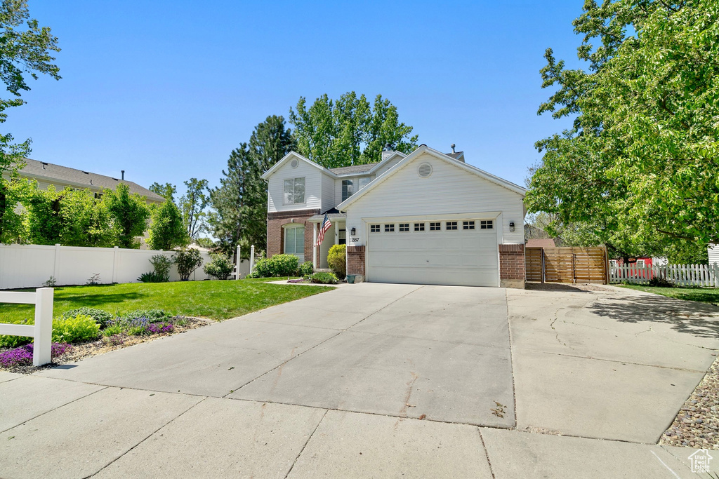 Traditional home featuring a garage, concrete driveway, a front yard, and brick siding