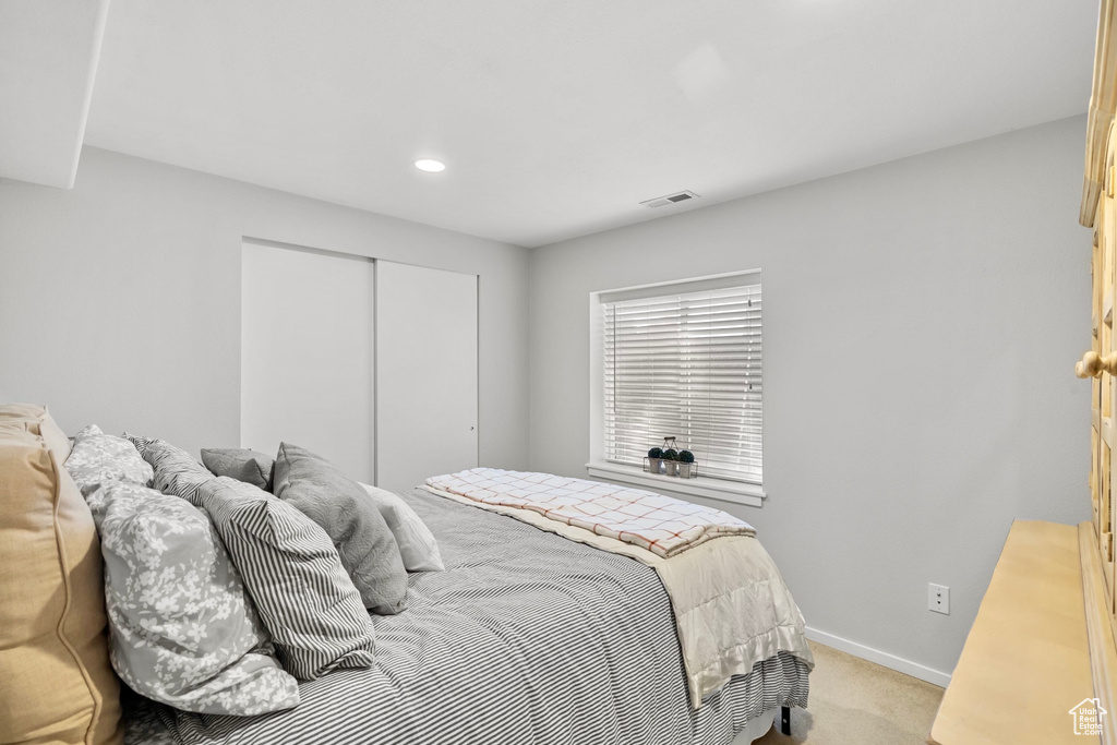 Bedroom with visible vents, baseboards, a closet, light carpet, and recessed lighting