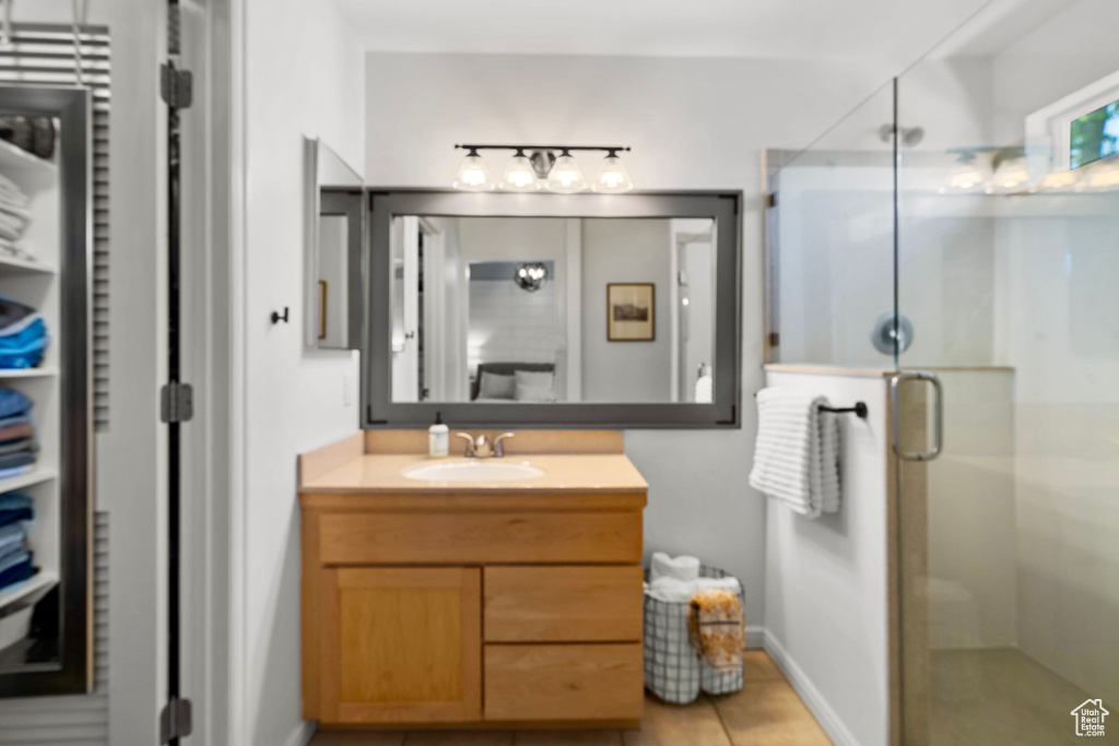 Full bath with vanity, baseboards, a shower stall, and tile patterned floors