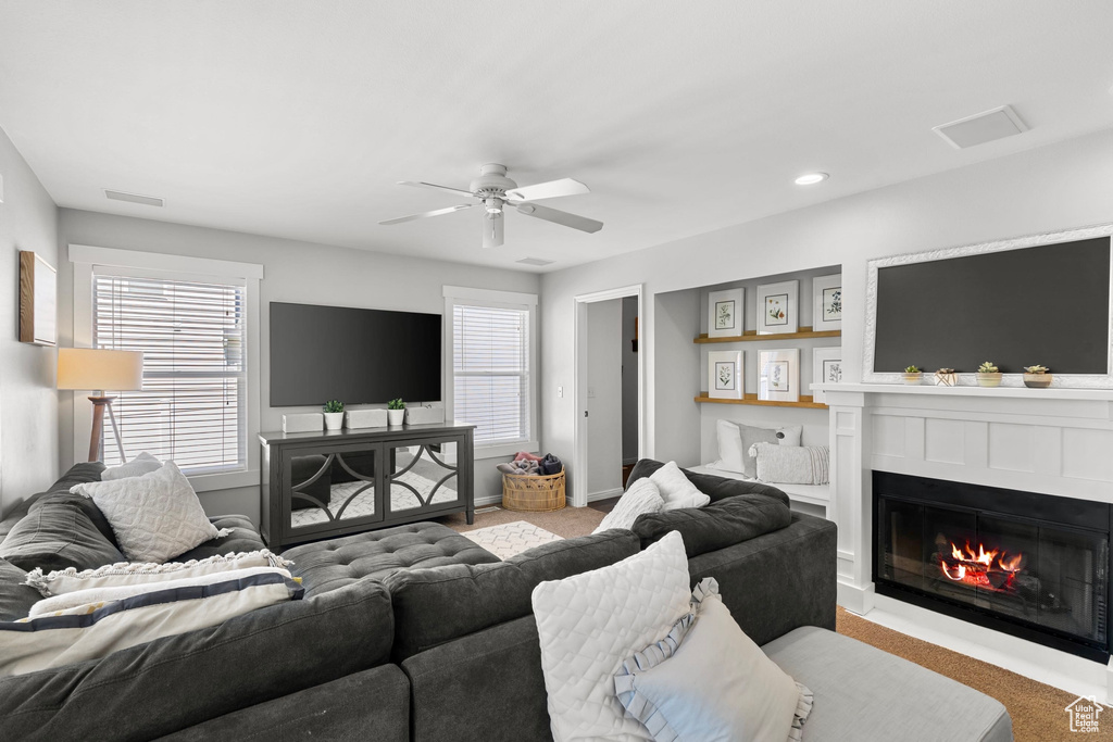 Carpeted living area featuring a glass covered fireplace, ceiling fan, recessed lighting, and visible vents