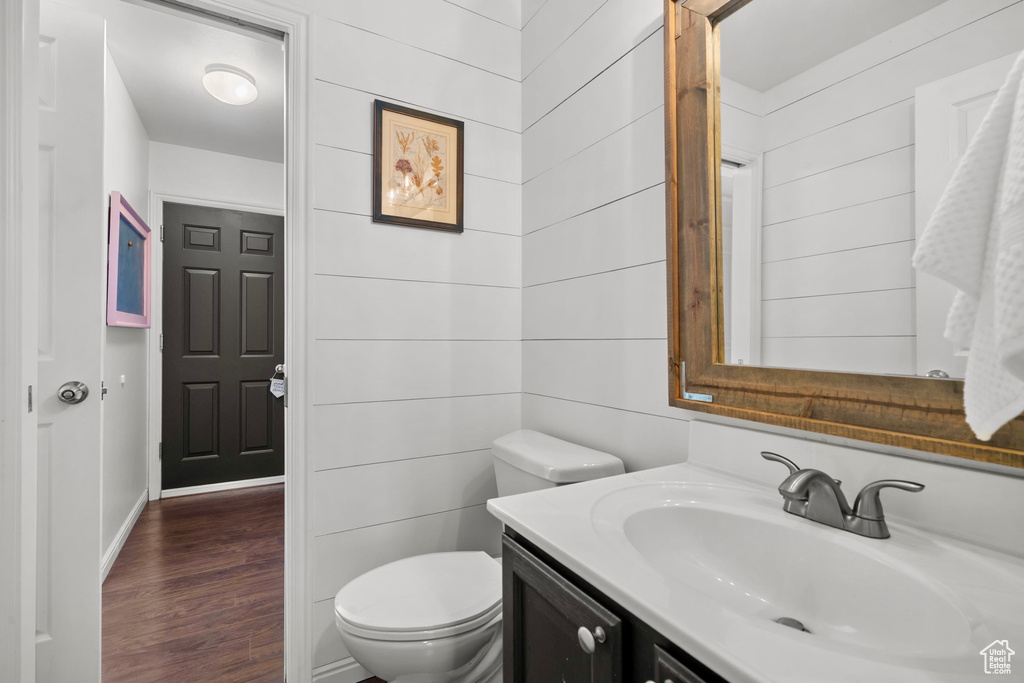 Bathroom featuring vanity, baseboards, wood finished floors, and toilet