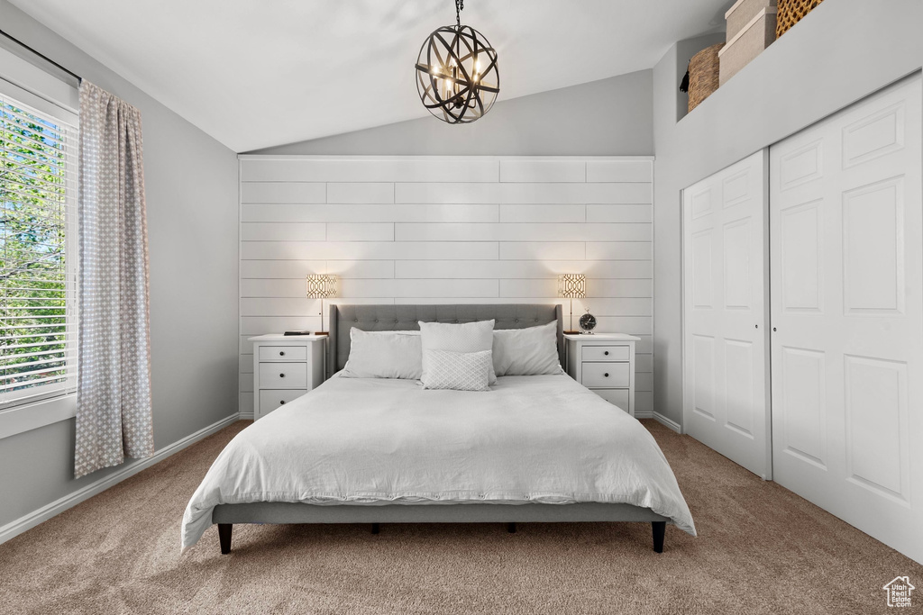 Bedroom featuring baseboards, a closet, lofted ceiling, an inviting chandelier, and carpet flooring