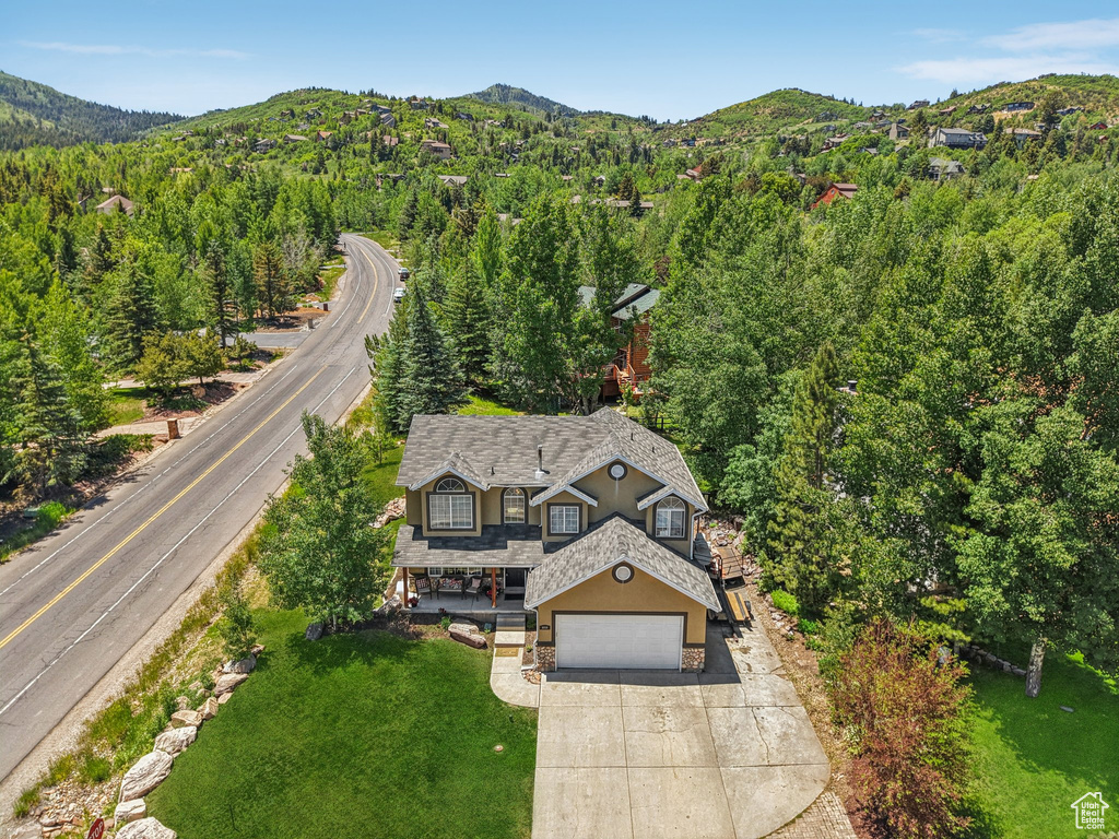 Aerial view of property and surrounding area featuring a mountainous background and a forest