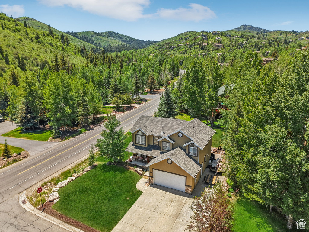 View from above of property featuring a mountain backdrop and a heavily wooded area