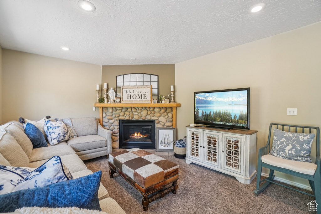 Living area featuring carpet floors, a stone fireplace, recessed lighting, and a textured ceiling