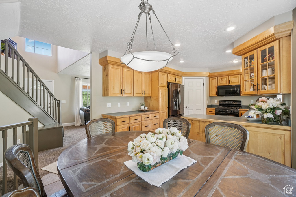 Dining area with a textured ceiling, stairs, recessed lighting, and light carpet