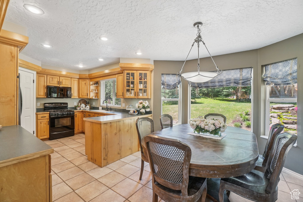 Kitchen featuring black appliances, a peninsula, open shelves, light tile patterned flooring, and glass insert cabinets