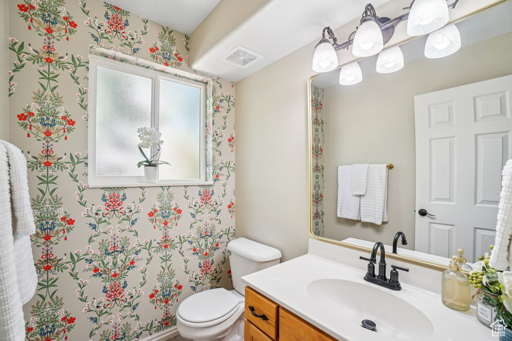 Bathroom with vanity and wallpapered walls