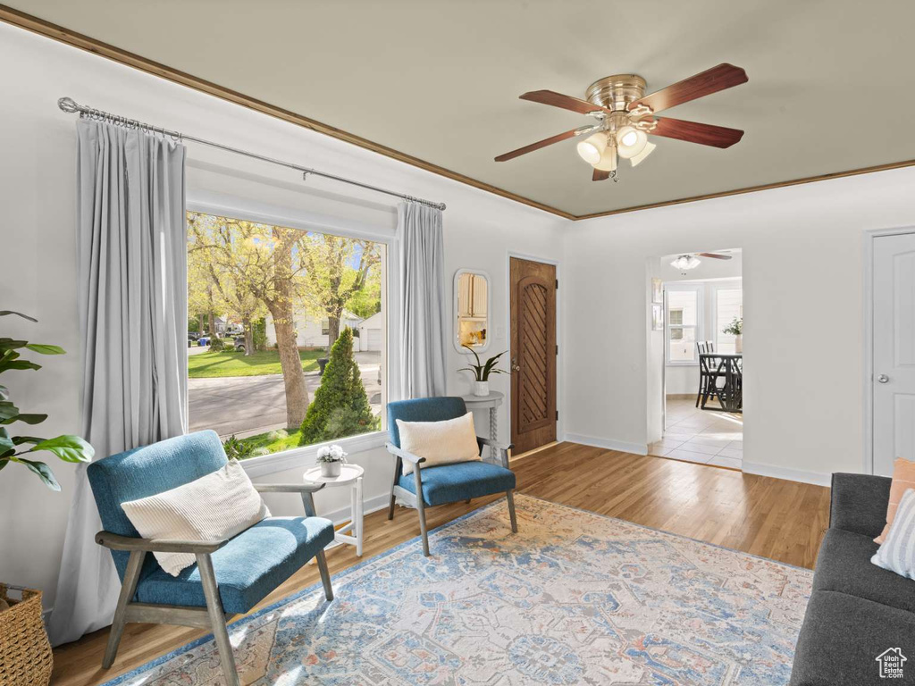 Sitting room featuring crown molding, baseboards, a ceiling fan, and wood finished floors