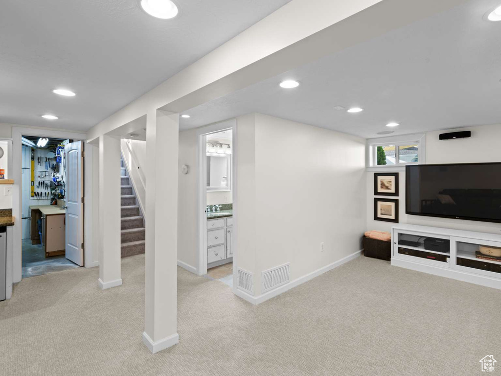 Basement featuring baseboards, light carpet, and stairs