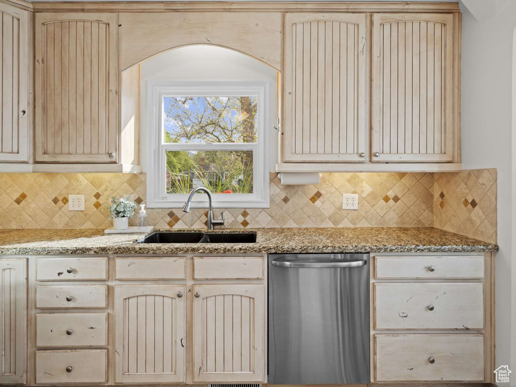 Kitchen with a sink, decorative backsplash, stainless steel dishwasher, and light stone countertops